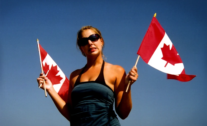 woman in bathingsuit holding two canadian and white flags