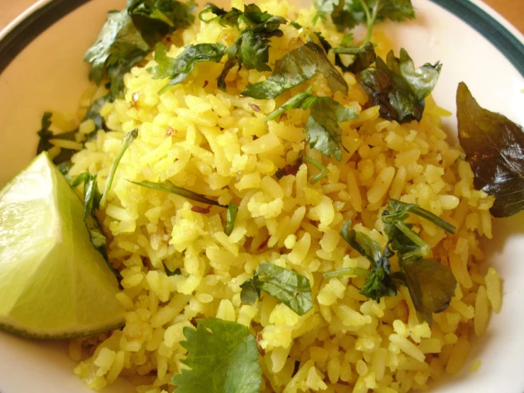 a bowl of rice is on a table with a lime and some sliced greens