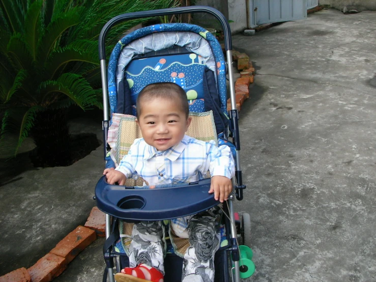 a  sitting in a stroller with a baby seat on top