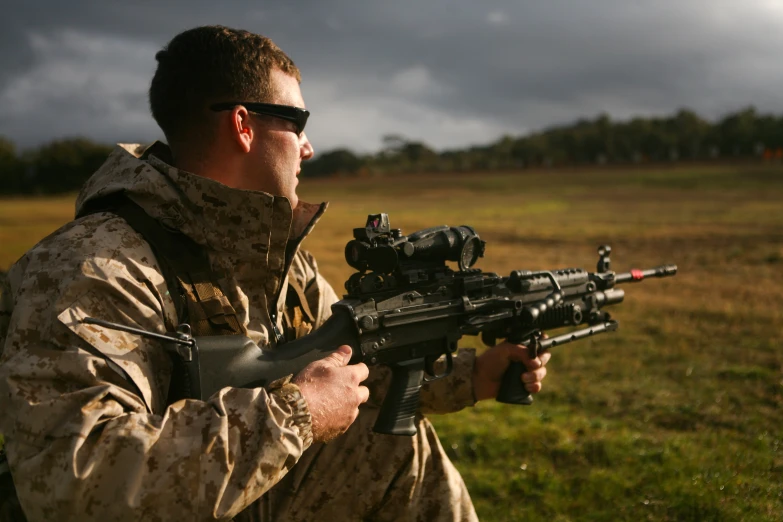 man in camouflage holding up a machine gun