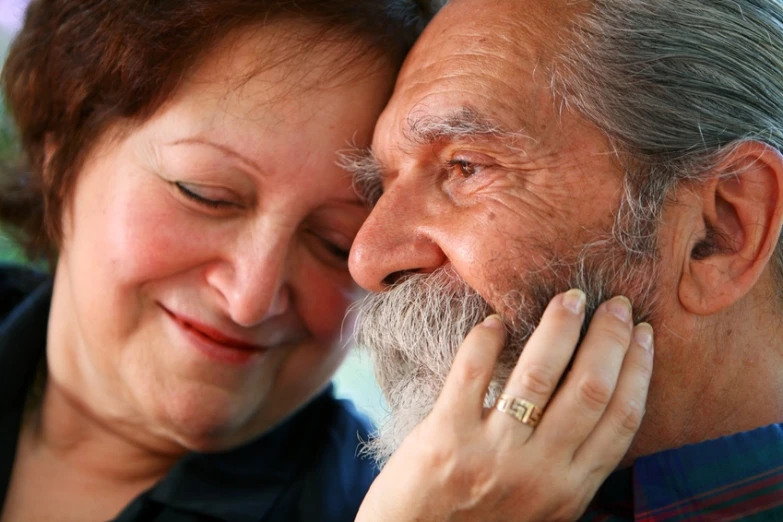 a smiling woman holds a ring on her face as an old man's face surrounds her