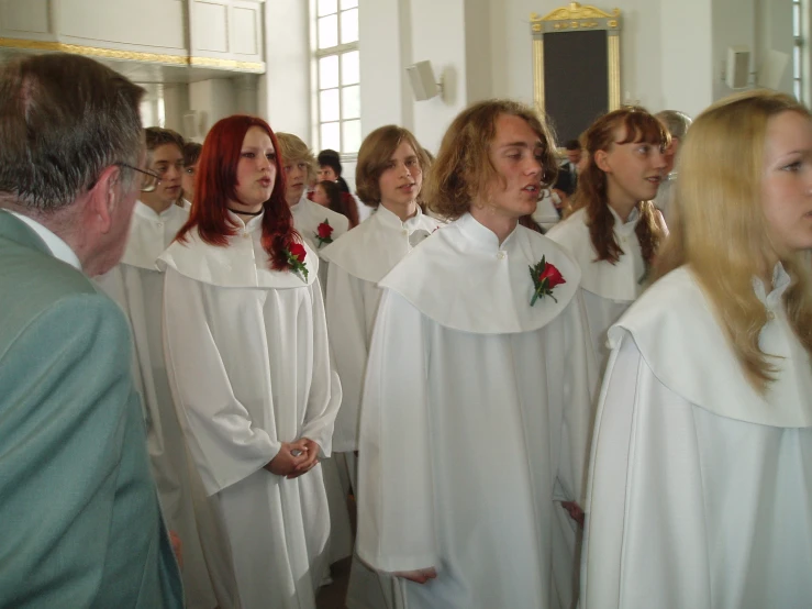 a group of people standing in front of each other wearing white robes