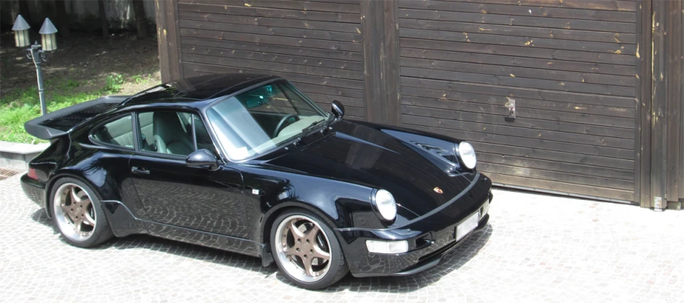 a black porsche parked in front of a garage