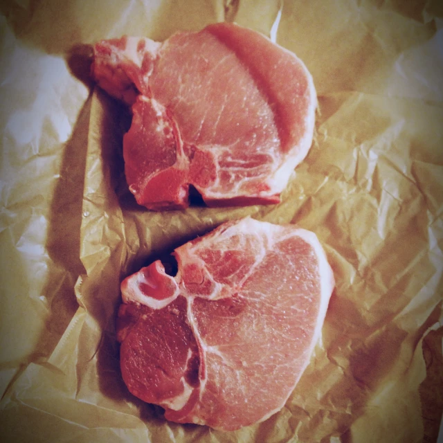 two raw pork chops laying on top of each other