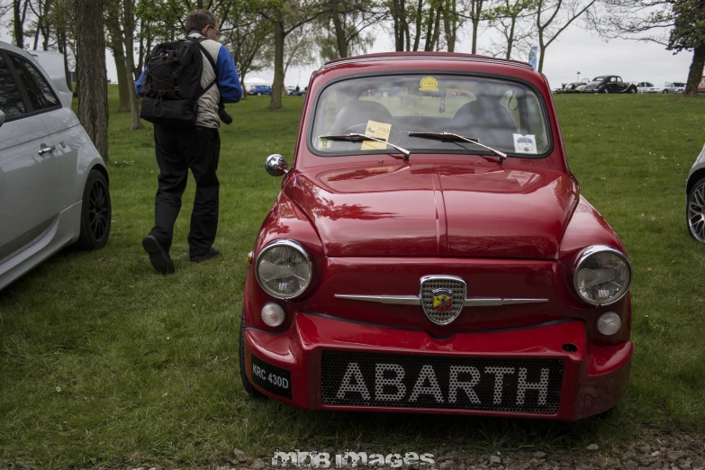 a small car parked near some cars in a field