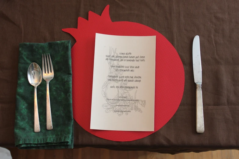 a place setting with silverware, silverware and letter on red paper