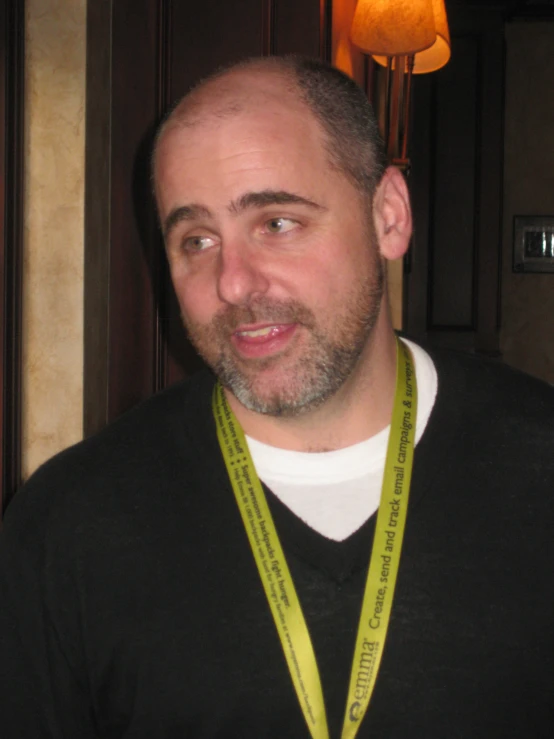 a man wearing a long green lanyard is posing for the camera