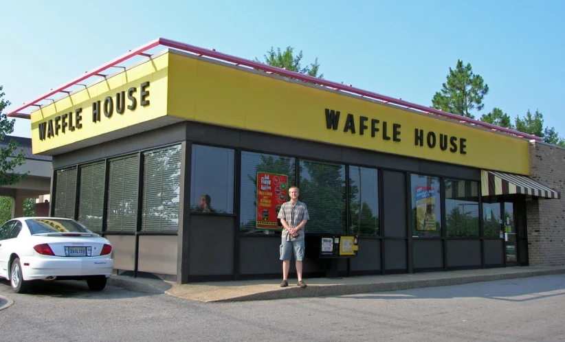 there is a man standing outside the waffle house restaurant