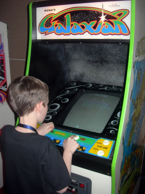 a young man plays with a toy version of the arcade machine