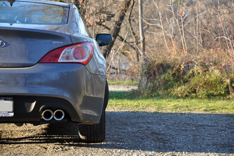 a back view of a silver car parked on the road