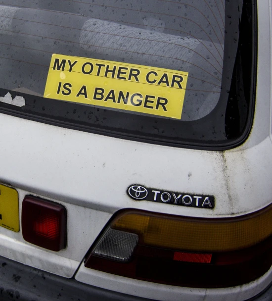 a yellow car is parked on the street with a sticker of toyota