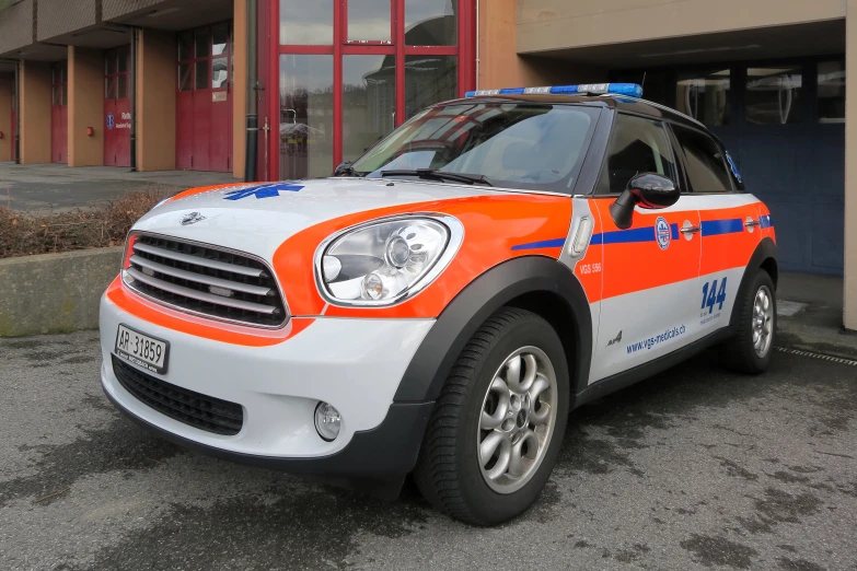 the front of an orange and white police car parked in front of a building