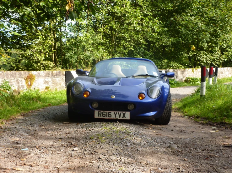 a blue sports car with the hood down parked on the road