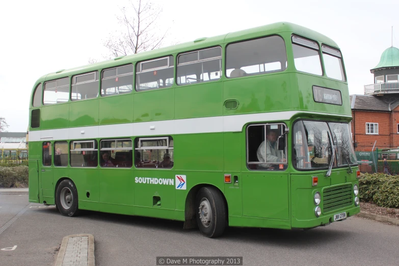 a green bus with a green roof is parked on a street