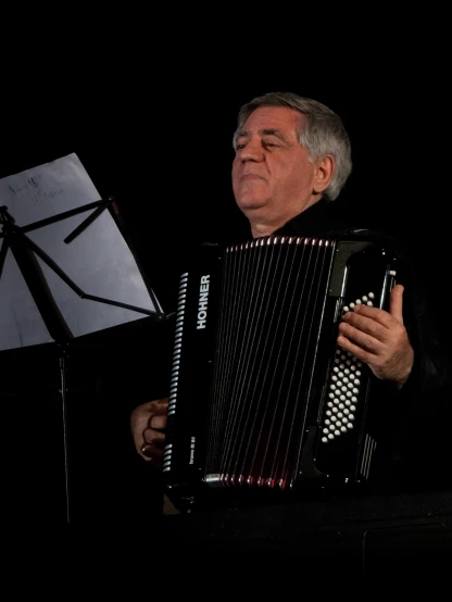 a man playing an accordion in a black room