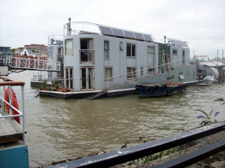 a houseboat floating down a river under a cloudy sky