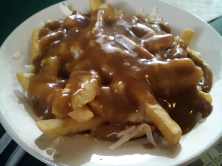 a plate of meat and fries covered in gravy