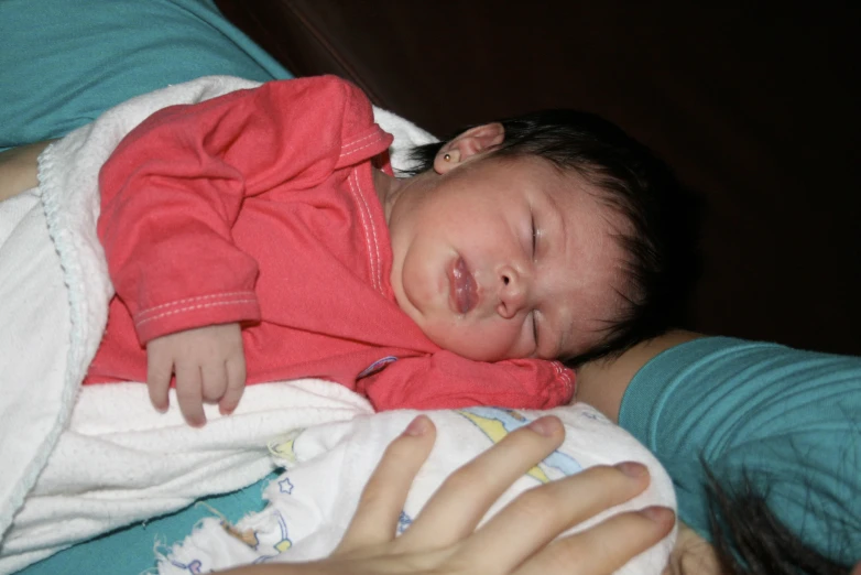 a woman is holding a sleeping child in her lap