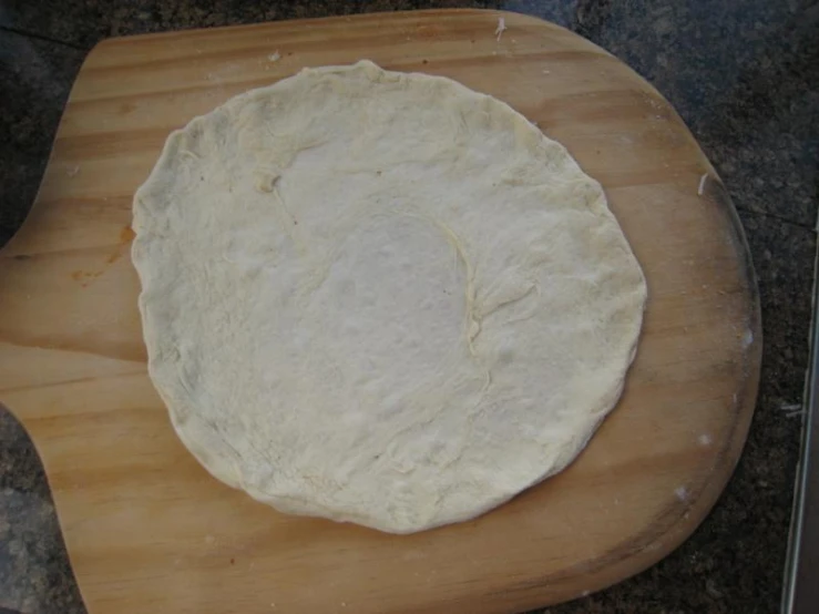dough is placed in a round on a wooden board