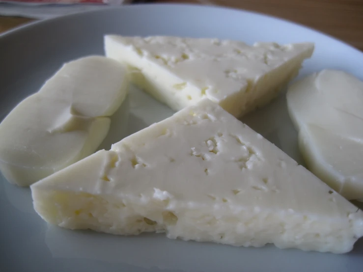 four pieces of white cheese on a plate