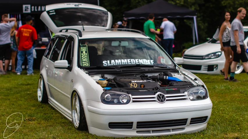 the vw golf is parked in a park with a hood up
