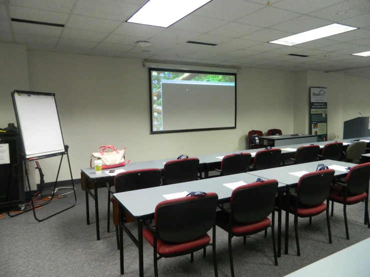 classroom with many tables and chairs and projection screen