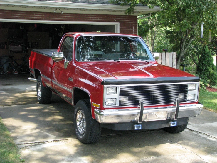 the red truck is parked in front of a garage