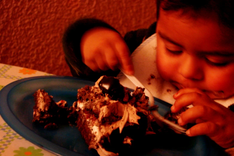 little boy with fork eating a chocolate desert