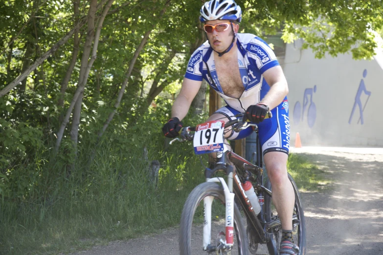 a cyclist in blue jersey riding on dirt road