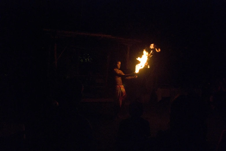 a woman is holding a lit fire in the dark