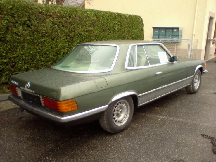 a green mercedes parked in front of a house