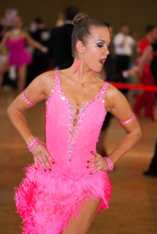 a woman in a pink leotard with feathers on her waist