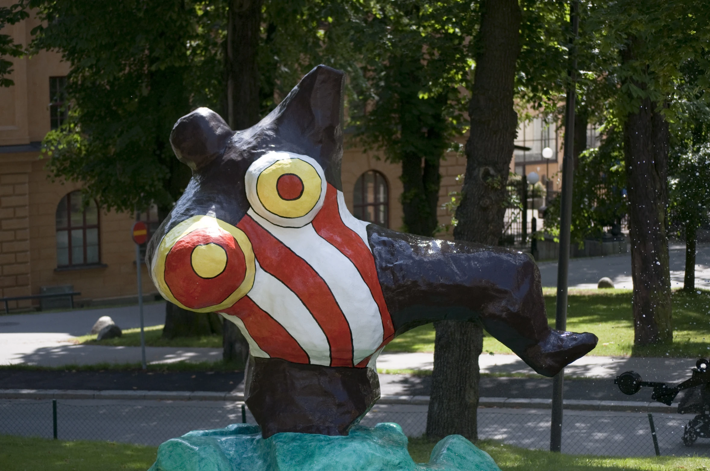 a colorful statue in a park next to trees