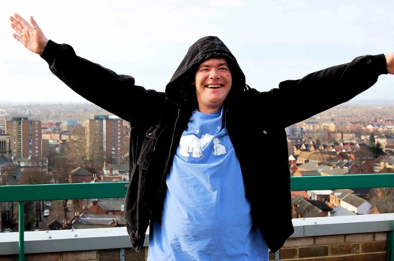 a man posing in front of a picture overlooking a city