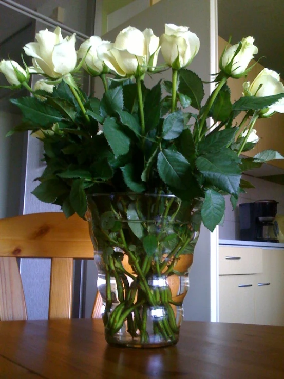 a glass vase filled with lots of white roses