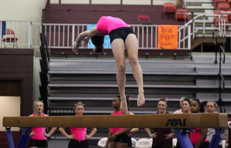 a woman doing a trick on the beam on the gymnastics competition