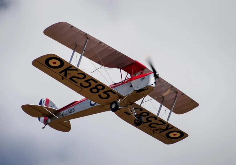 a biplane flies sideways in the air on a sunny day