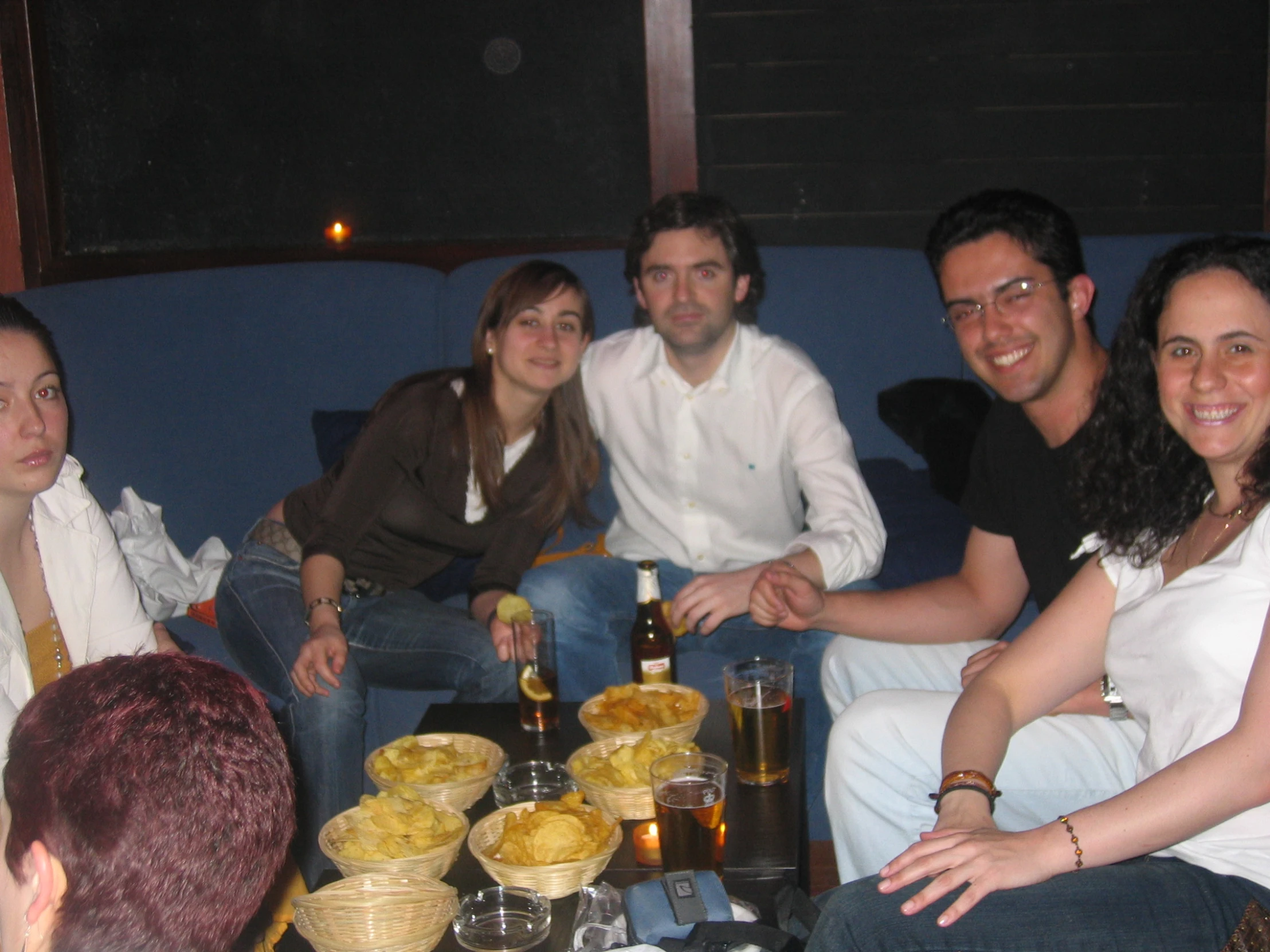 several people sitting at a table with food and drinks