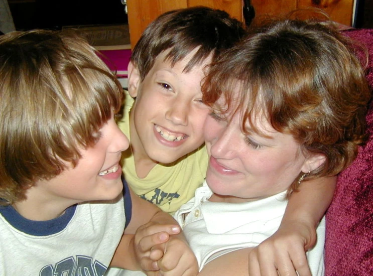 three boys and a woman smile as they lie down together