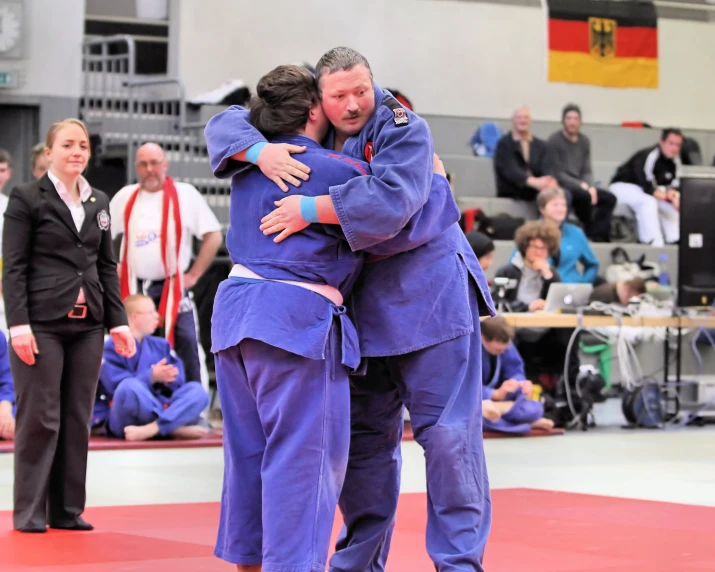 two people are hugging on a red mat