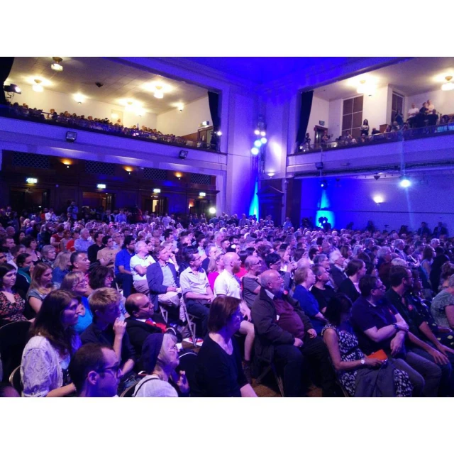 an auditorium full of people with purple lighting