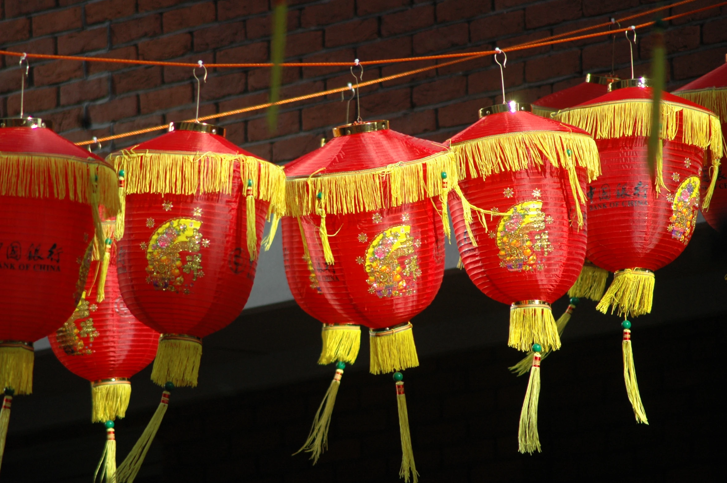 chinese paper lanterns hang from strings over brick wall