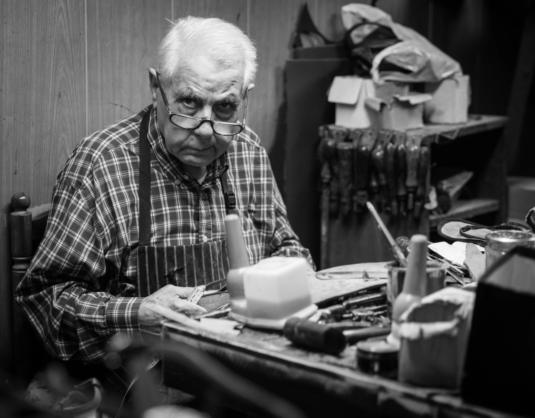 an old man sitting at a desk working on his nails