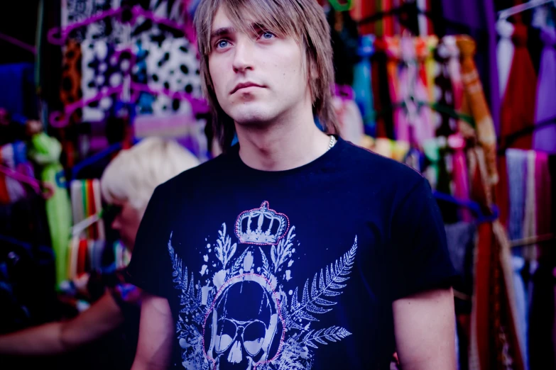 a man with long hair wearing a skull tee shirt in a clothing shop