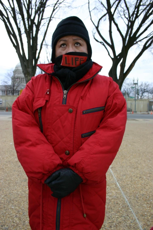 a person in a red jacket is wearing a black cap