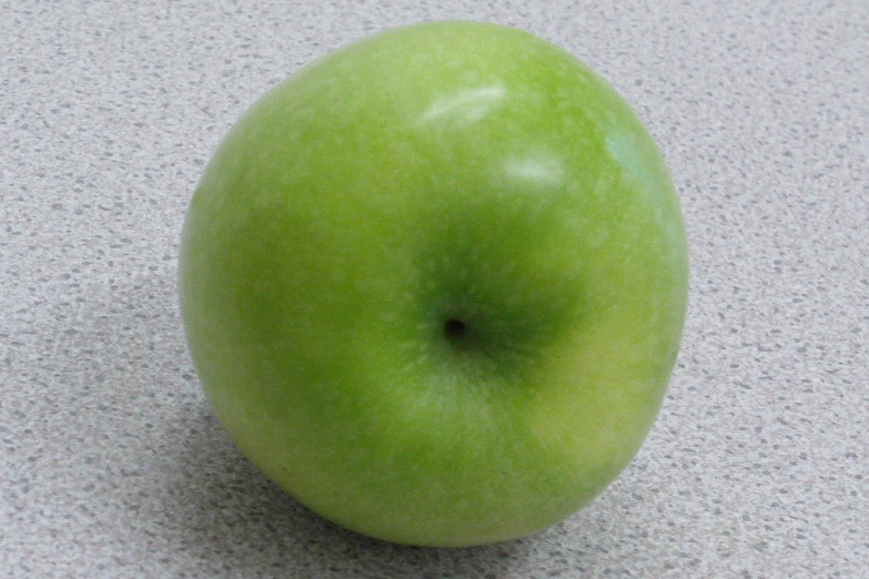 an apple on the ground, possibly a green apple