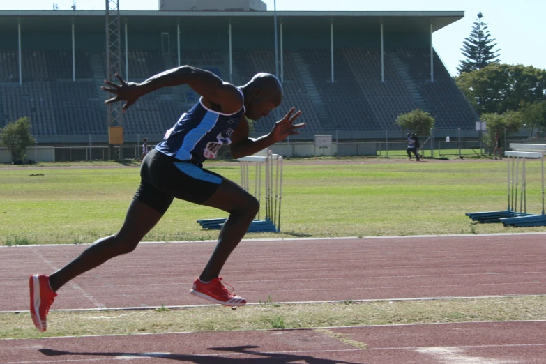 a male athlete in a blue and black shirt is on the track