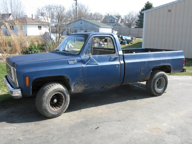 an old blue pick - up truck parked on a driveway