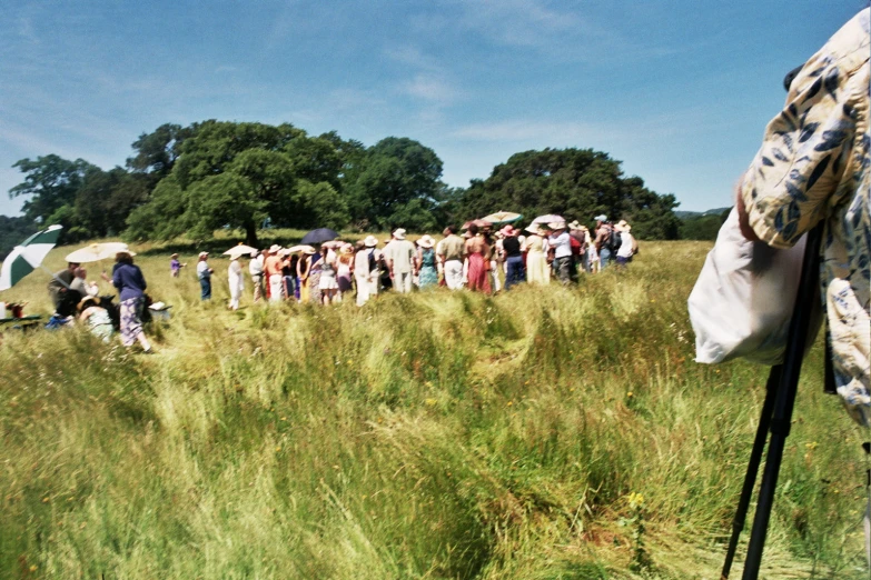 group of people in dress clothes walking through tall grass