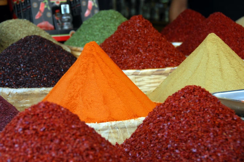 several bowls of brightly colored spices and spoons